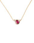 The 14k Garnet Bezel Necklace features a single round, ethically sourced garnet set in a simple gold bezel on a delicate 14k gold chain, shown against a white background.
